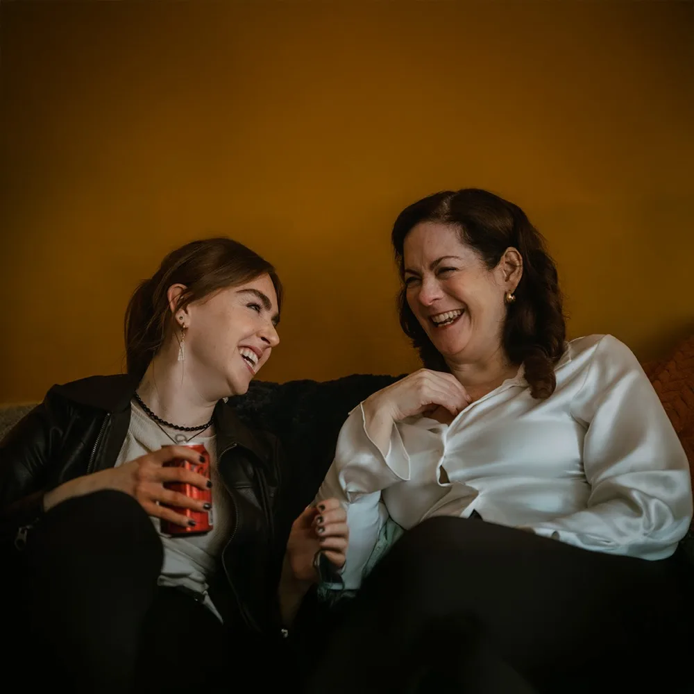 Yvonne and her mother Maria laughing together on the sofa