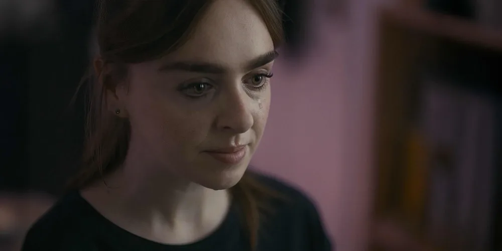 Close-up of Yvonne, tearful, in her bedroom